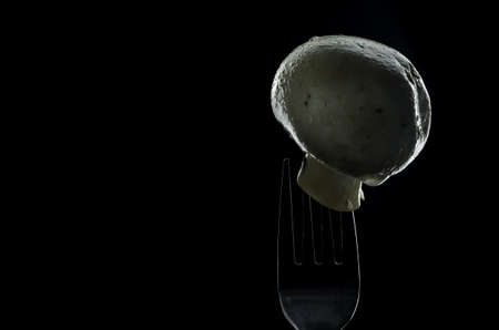 mushroom champignon is on a fork background blackの写真素材