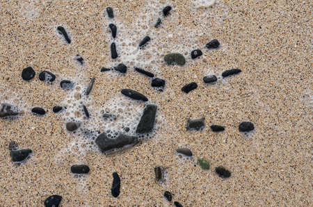pattern of the sun of a black stone on sand top viewの写真素材