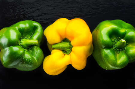 three green yellow sweet pepper on slate. top viewの写真素材