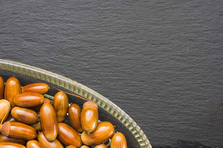 Acorns in a dish on a dish for the supply of slate left bottom top viewの写真素材