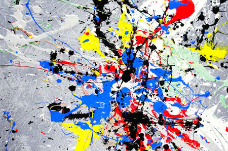a spot of white and black and yellow and green and red and blue spilled paint on a concrete textured surface.の写真素材