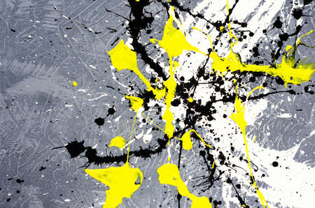 a spot of white and black and yellow spilled paint on a concrete textured surface.の写真素材