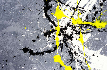 a spot of white and black and yellow spilled paint on a concrete textured surface.の写真素材