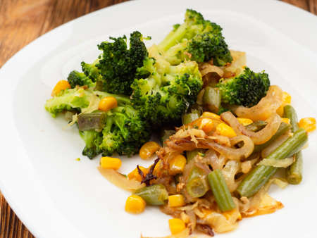 cooked vegetables broccoli, carrots, green beans, corn on a white plate. closeupの写真素材
