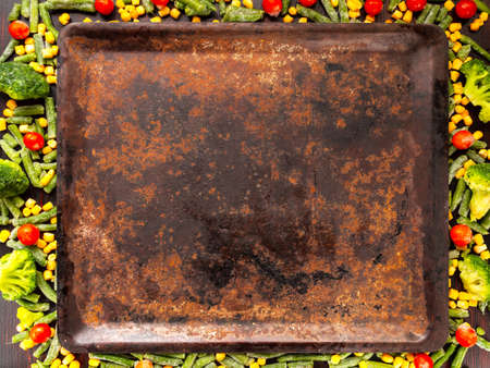 Food background with free space for text. broccoli, corn, green beans, tomatoes around a baking sheet. View from above.の写真素材