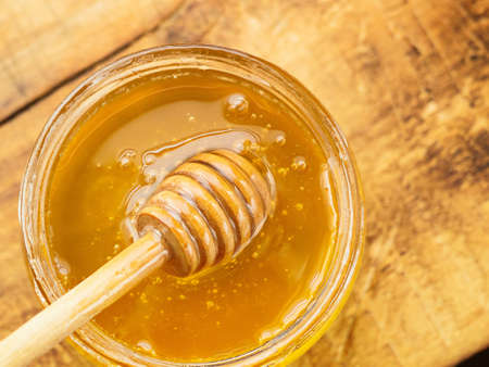 honey with wooden dipper top viewの写真素材