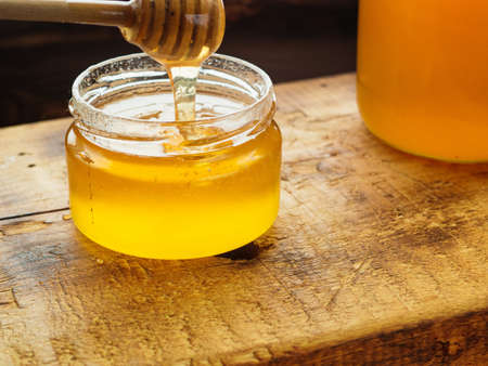 Glass jar with sweet honey on wooden board.の写真素材