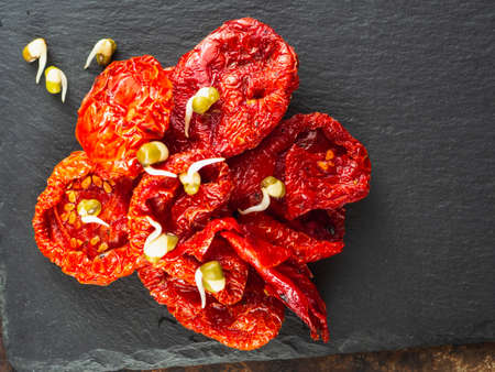 A pile of sun-dried tomatoes, and soybean seeds of sprouted mung beans. Are on Natural Slate Dishes . Horizontal orientation. close-up. flat lay top view.の写真素材