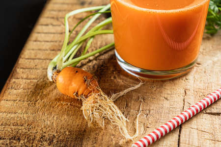 one litle ugly carrot. Glass with freshly squeezed carrot juice. one ugly carrot with green leaves....