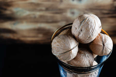 walnuts in a wine glass. On a wooden background. On a dark wet table. Horizontal orientation. copy space. close upの写真素材
