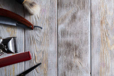 barber tools hairdressing scissors vintage manual clipper comb brush dangerous razor are on a white weathered wooden surface. copy space. Vertical orientation. Close-up. flat lay. top viewの写真素材