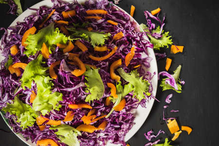 head lettuce bell pepper red cabbage salad casually scattered around a flat dish. Black background. top view. horizontal. copy spaceの写真素材
