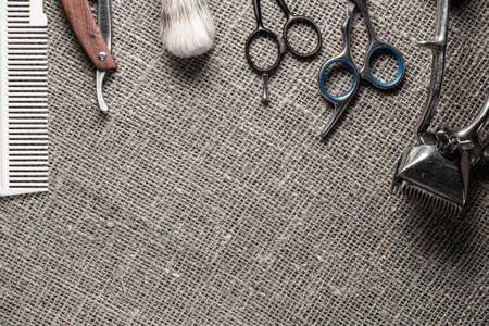 vintage barber tools dangerous razor hairdressing scissors old manual clipper comb shaving brush. on sackcloth background. copy space top view flat lay. Horizontal.の写真素材