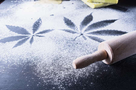 The process of making cannabis pastries. You can see a rolling pin, traces of marijuana leaves on flour, and tiles hashish oil. Horizontal orientationの写真素材