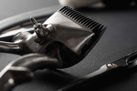 On a black surface are old barber tools. vintage manual hair clipper, razor, comb, shaving brush,...