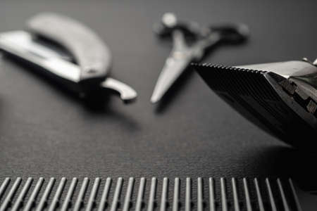 black surface are old barber tools. two vintage manual hair clipper, razor, shaving brush, hairdressing scissors. black monochrome. horizontal orientation.の写真素材