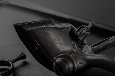 On a black surface are old barber tools. vintage manual hair clipper, hairdressing scissors. black monochrome. vertical orientation.の写真素材