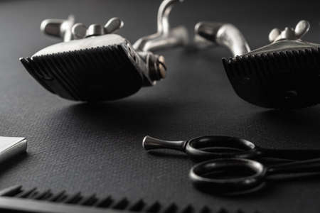 On a black surface are old barber tools. vintage manual hair clipper, razor, comb, hairdressing scissors. black monochrome. horizontal orientation.の写真素材