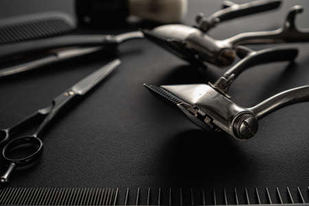 On a black surface are old barber tools. Two vintage manual hair clipper, comb, razor, shaving brush, hairdressing scissors. black monochrome. horizontal orientation.の写真素材