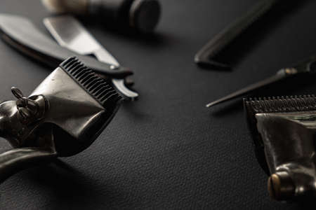 On a black surface are old barber tools. Two vintage manual hair clipper, razor, shaving brush, hairdressing scissors. black monochrome. horizontal orientation.の写真素材