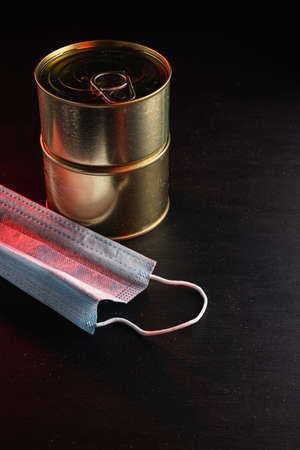 medical mask and two cans of canned food on a dark background. dramatic. vertical. copy space