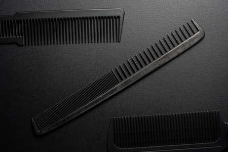 On a black surface are old barber tools. barber tools. three comb. black monochrome. frame. top view flate lay.の写真素材