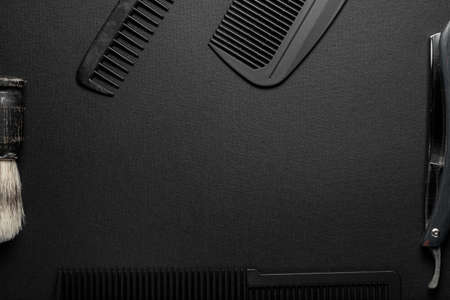 On a black surface are old hairdresser tools. combs, razor, shaving brush. black monochrome. horizontal orientation. top view flat ley. frame copy spaceの写真素材