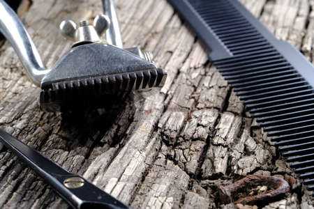 On a old wooden surface are old barber tools. Vintage manual hair clipper comb razor shaving brush hairdressing scissors. horizontal orientation.の写真素材