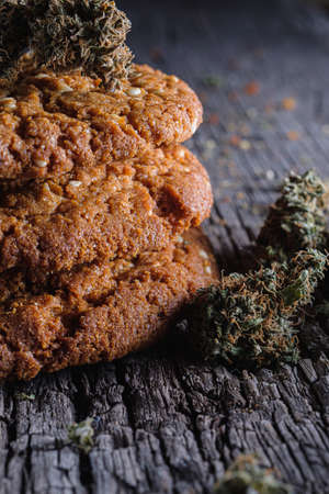 biscuits with marijuana on an old wooden background close-up. Healthy food with medical cannabis. the buds are inaccurately scattered. rustic. Vertical orientation.の写真素材