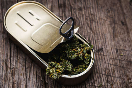 cannabis in a open tin can. on old wooden background. rustic. Horizontal orintation