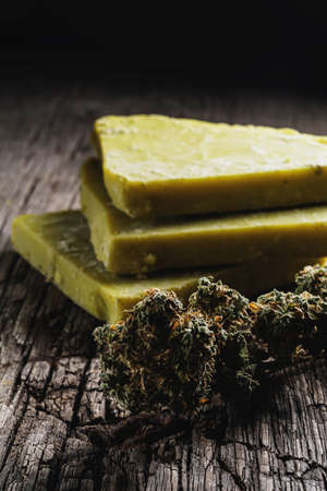 rustic cannabis butter and medical marijuana bud on old rust metal dripping pan. old wooden background. vertical orientation. close-up.の写真素材