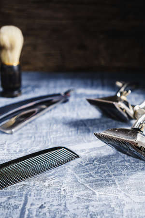 On a painted concrete surface are old hairdresser tools. two vintage hand-held hair clipper, hairdressing scissors, combs, razor, shaving brush. vertical orientation.の写真素材