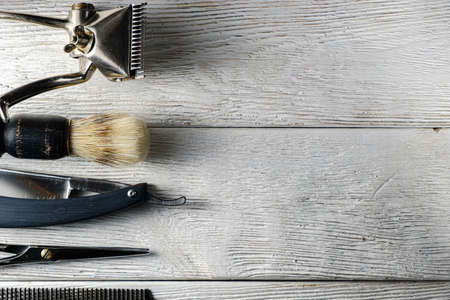old hand hairdressing tools. Manual clipper, hairdressing scissors, straight razor, brush for shaving foam. on white weathered wood background. top view flat layの写真素材