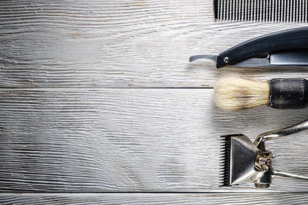 old hand hairdressing tools. Manual clipper, hairdressing scissors, straight razor, brush for shaving foam. on white weathered wood background. top view flat layの写真素材