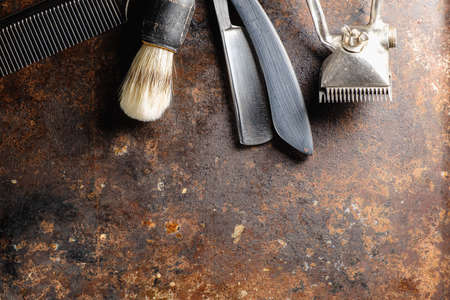 On a rusty surface are old hairdresser tools. manual clipper, comb, razor, shaving brush. rustic. horizontal. top view. flat ley. copy space.の写真素材