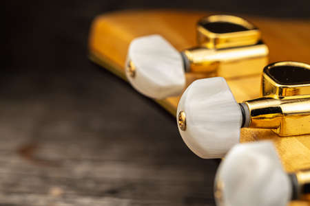 Head of old acoustic golden guitar on wooden. Macro photo. Horizontal orientation