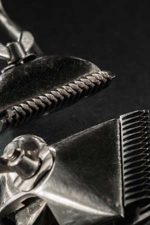 On a black surface are old barber tools.Two vintage manual hair clipper. black monochrome. Close-up....