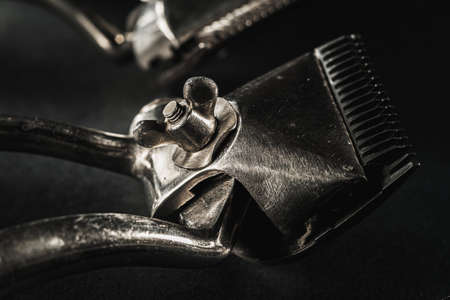 On a black surface are old barber tools.Two vintage manual hair clipper. black monochrome. Close-up. Barbershop background. contrast shadows. Horizontal orientationの写真素材