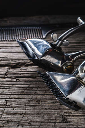 On a old wooden surface are old hairdresser tools. two vintage hand-held hair clipper and comb. vertical orintationの写真素材