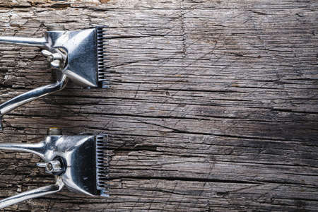 On a old wooden surface are old hairdresser tools. two vintage hand-held hair clipper. Masculine, flat lay, top view. Horizontal orientationの写真素材