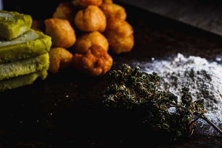 churros balls spanish donuts from medical cannabis butter, sugar, flour, egg. Nearby are marijuana buds. cannabis butter, a heap of flour. On a rusty baking sheet. horizontal orientation.の写真素材