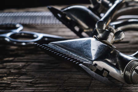 On a old wooden surface are old hairdresser tools. two vintage hand-held hair clipper and comb and seen hairdressing scissors. horizontal orintationの写真素材