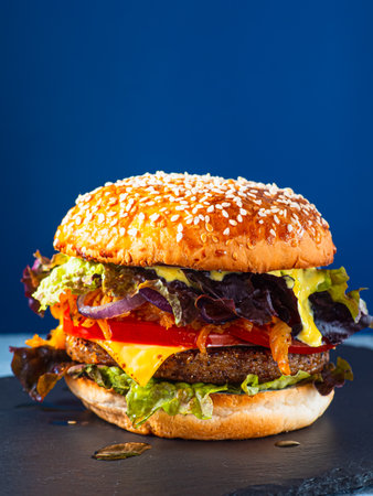 Vegan burger on a slate plate. blue background. Vertical.の写真素材