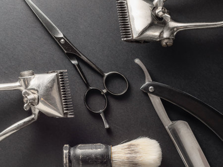 This display features traditional barber tools including clippers, scissors, and a razor on a dark surface. Each tool reflects the craftsmanship and history of grooming practices.の写真素材