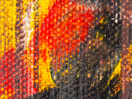 A captivating abstract piece features a blend of red, yellow, and black colors, creating energetic movement within the artwork displayed at an urban gallery during daylight.の写真素材
