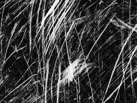 A close-up view reveals an intricate pattern of white scratches against a dark background, showing...