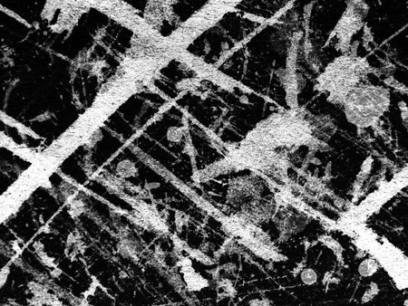 A detailed view of a black surface marked by light scratches and streaks, showing the interplay of...