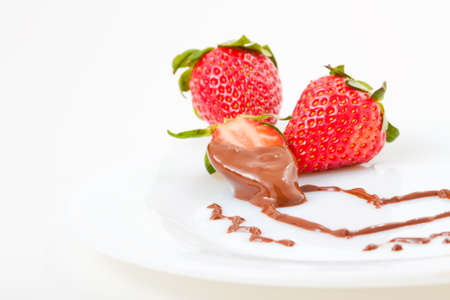 Strawberries on plate in chocolate heart shaped form.の写真素材