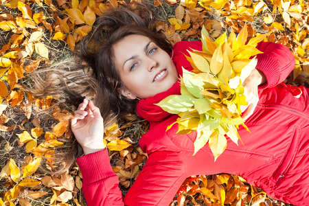 Young woman with autumn leaves and fall yellow maple garden background