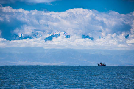 Boat on horizon between lake and mountainの写真素材